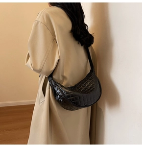Detailed view of black quilted saddle bag featuring sleek rhombic stitching on PU material