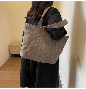 Side view of taupe quilted tote bag with diamond stitching on a female model
