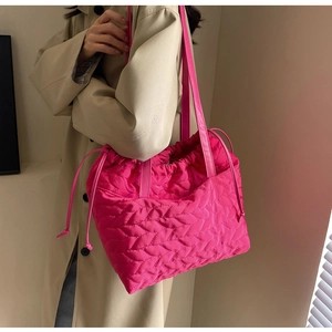 Detail of rose red quilted tote bag with drawstring closure and wavy texture finish