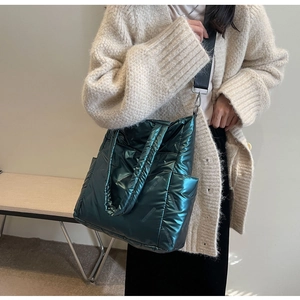 Detail view of deep green quilted tote bag with metallic finish and wide shoulder strap