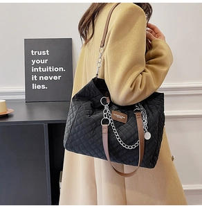 Détail du sac fourre-tout en nylon matelassé avec bandoulière en cuir brun et chaîne