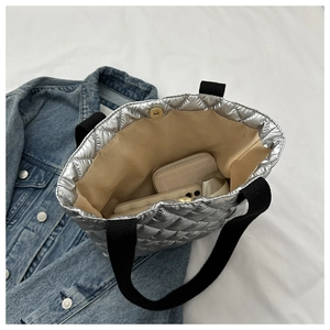 Detail view of silver quilted tote bag with magnetic closure and spacious inner storage