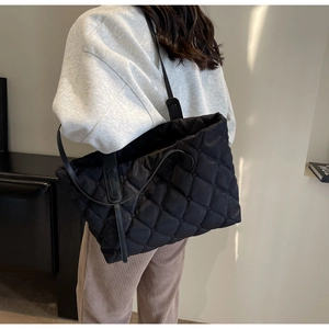Rückansicht eines Models mit großer schwarzer gesteppter Shopper-Tasche mit Trägern