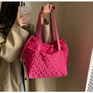 Detail of bright pink quilted tote bag with wavy bubble texture and drawstring closure