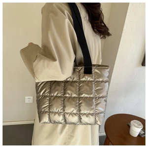 Detail view of champagne gold quilted tote bag with black fabric shoulder straps