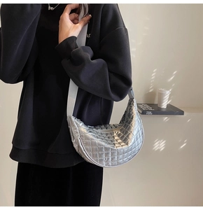 Detail shot of silver quilted crescent bag featuring wide strap and metallic grid texture
