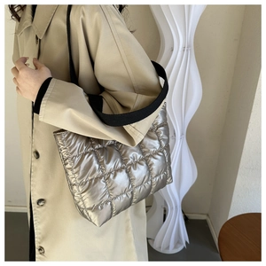 Detail of silver quilted metallic shoulder bag with black strap and shiny grid texture