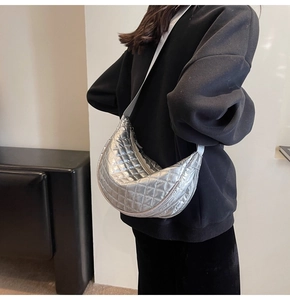 Detail of silver quilted crescent bag with adjustable wide strap shown on model's shoulder