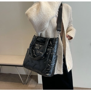 Detailed shot of a black quilted shoulder bag with glossy pearl finish on premium fabric