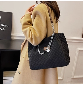 Détail du sac cabas matelassé en nylon noir avec cuir marron et chaîne argentée