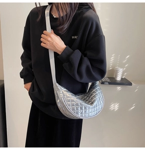 Chic silver quilted half-moon crossbody bag with metallic finish shown on model