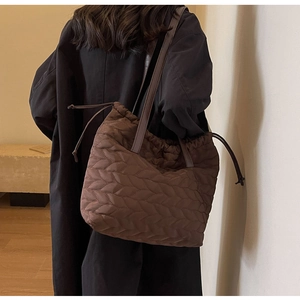 Detail of dark brown quilted tote bag showing leaf-pattern texture and drawstring closure