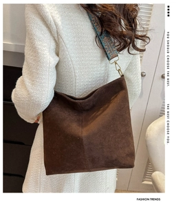 Close-up of brown suede hobo bag with a vintage patterned wide woven strap