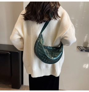 Quilted dark green crescent crossbody bag with adjustable wide strap on model