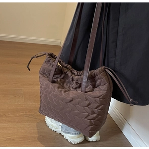 Detail of brown quilted nylon shoulder bag with leaf stitching and drawstring closure