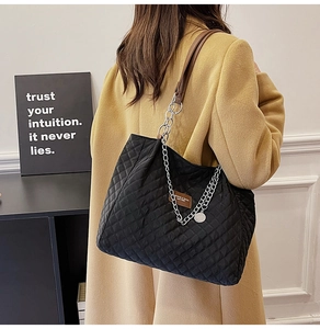 Détail d'un sac cabas en nylon matelassé noir avec bandoulière cuir et chaîne argentée