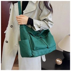 Practical multi-pocket canvas crossbody bag in dark green shown on a model