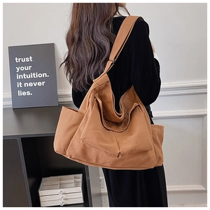 Detail view of large brown canvas shoulder bag with utility pockets and retro style
