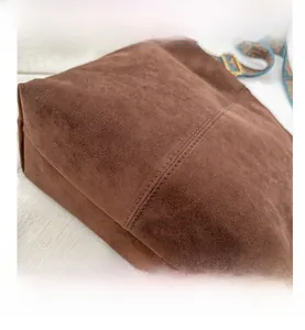 Detail of dark brown suede shoulder bag with ethnic jacquard strap and gold buckle