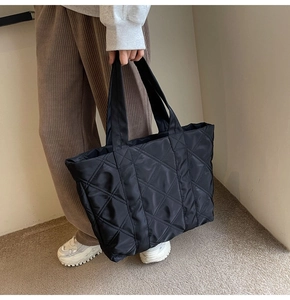 Close-up of black quilted nylon tote bag showing detailed diamond stitching and wide handles