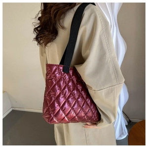 Chic burgundy quilted tote bag with metallic finish worn with a beige trench coat
