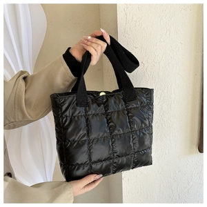 Detail of black quilted tote bag with glossy finish and secure gold magnetic buckle