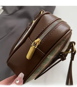 Close-up of premium golden metal zipper on a dark brown leather and wool shoulder bag
