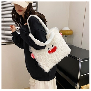 Gros plan détaillé d'un sac cabas en peluche blanche avec une broderie de bouche de monstre