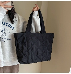 Close-up of black quilted tote bag with large capacity and reinforced shoulder straps