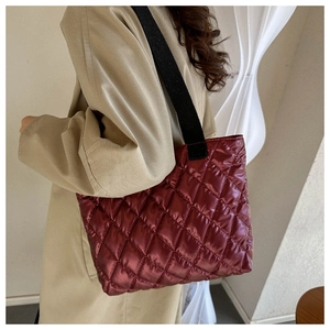 Close-up of wine red quilted tote bag with glossy finish on a stylish model