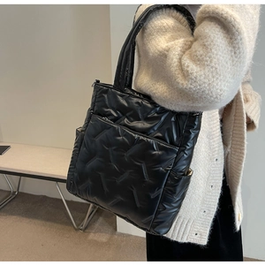 Detail shot of black quilted tote bag with herringbone pattern and front zipper pocket