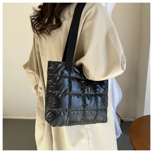 Rear view of model wearing black quilted nylon down tote bag with high-gloss finish