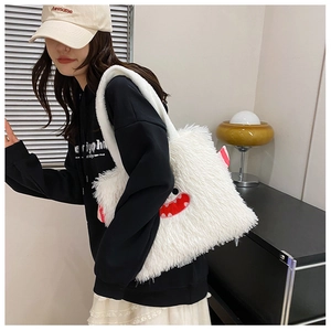 Détail du sac cabas en peluche blanche avec visage de monstre mignon et texture douce