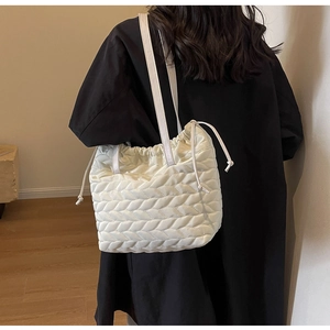 Close-up of cream quilted shoulder bag with drawstring closure and leaf pattern texture