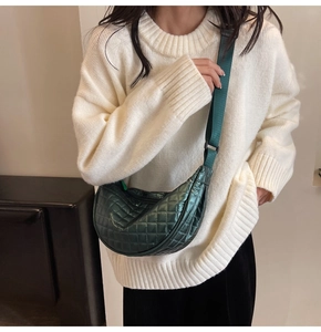 Close-up of dark green quilted crescent bag with adjustable strap and textured nylon surface