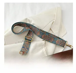 Close-up of printed shoulder strap with colorful geometric patterns and gold metal hardware