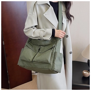 Olive green canvas crossbody bag featuring large front pockets and wide strap