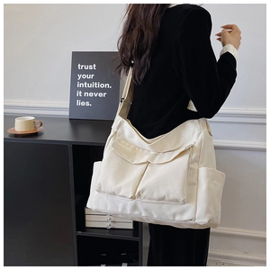Detail view of cream canvas crossbody bag with double front flap pockets on model