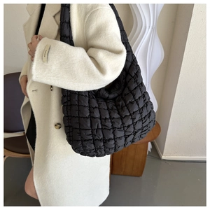 Détail du sac cabas rembourré noir avec surpiqûres en losange sur une femme