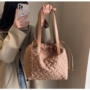 Close-up of brown quilted nylon tote bag with drawstring closure and leather straps