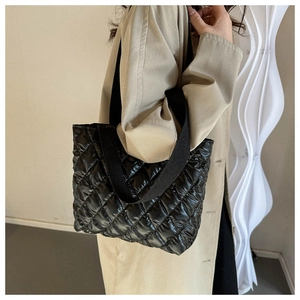 Detail of high-end black quilted puffer tote bag with wide shoulder strap and gloss finish