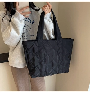 Woman carrying a black quilted tote bag with diamond pattern for casual daily styling