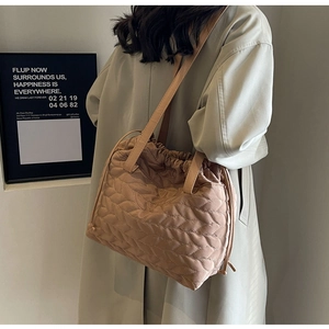 Detail view of light brown quilted shoulder bag with drawstring closure and puffy texture