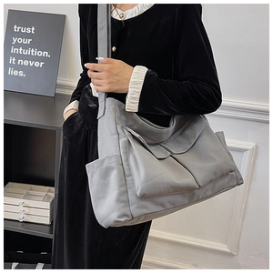 Detail view of a grey multi-pocket canvas crossbody bag with thick cotton texture