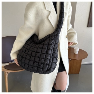 Détail du sac matelassé noir à texture bouffante porté sur un manteau beige élégant