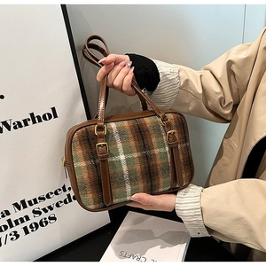 Close-up of retro plaid wool and brown leather shoulder bag with golden hardware