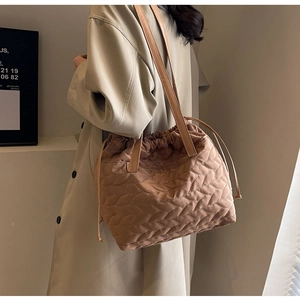Detail of wave quilted tote bag with drawstring closure and long leather handles