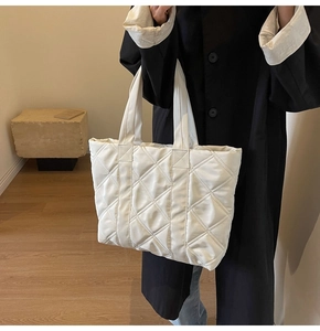 Detail view of a white quilted tote bag featuring large diamond stitching and soft fabric