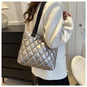 Close-up of a silver quilted shoulder tote bag with metallic gloss and black strap