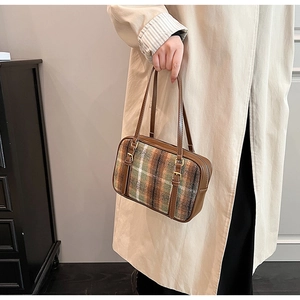 Close-up of a plaid wool shoulder bag with brown leather trim and metal buckles